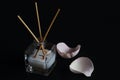 Aromatic glass diffuser with essential oil and reed sticks and pink rose petals on black background. Concept Ã¢â¬â home comfort